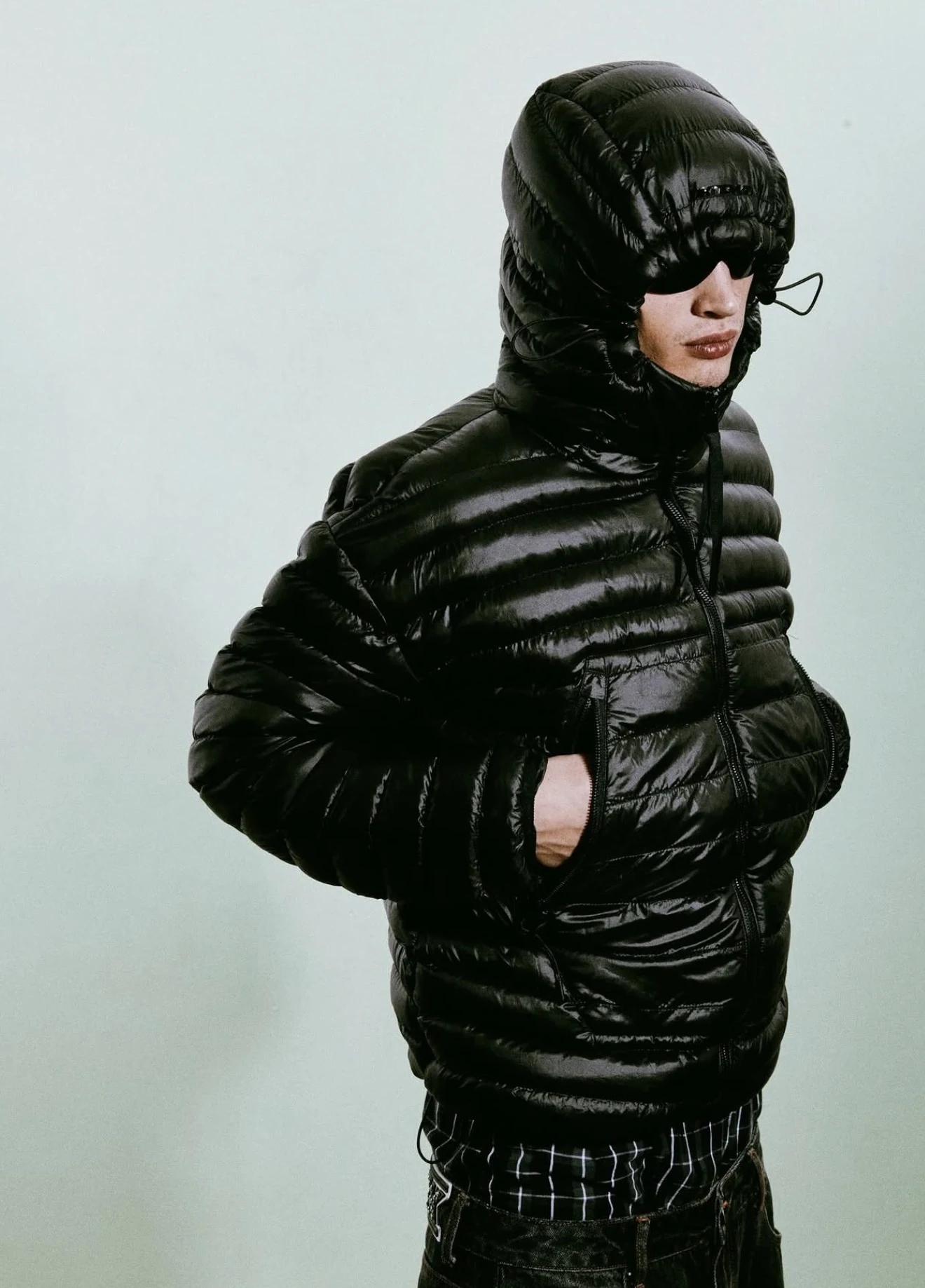Model wearing a black puffer jacket in an industrial setting