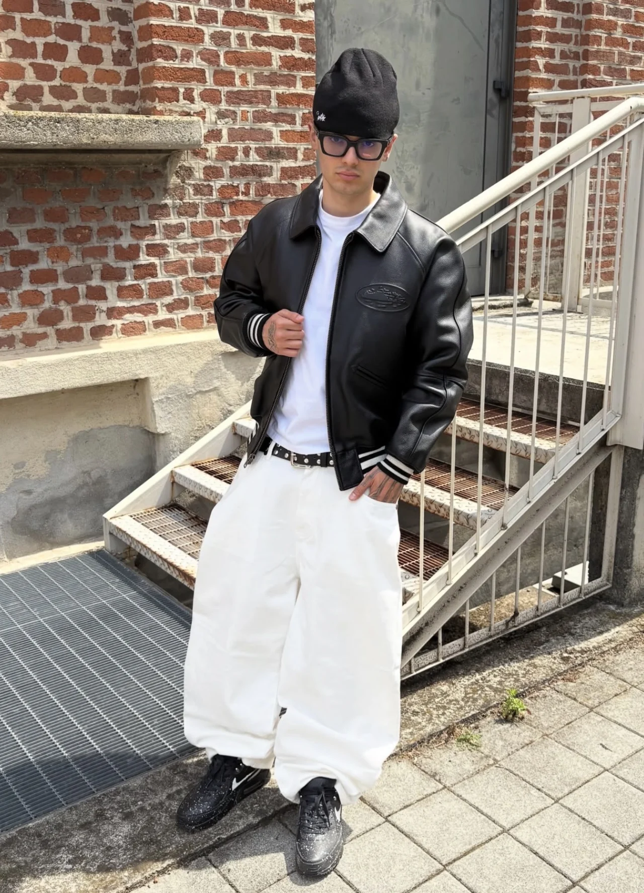 DACI wearing a black leather jacket and white trousers