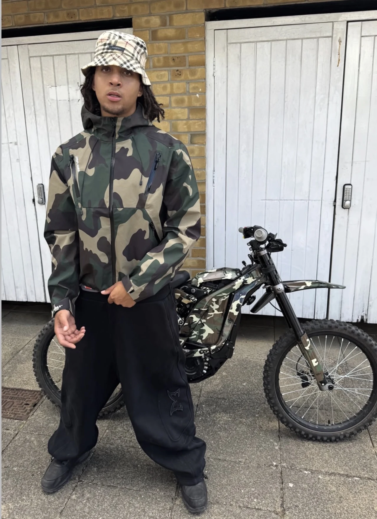 FIN wearing a camouflage jacket beside a bike