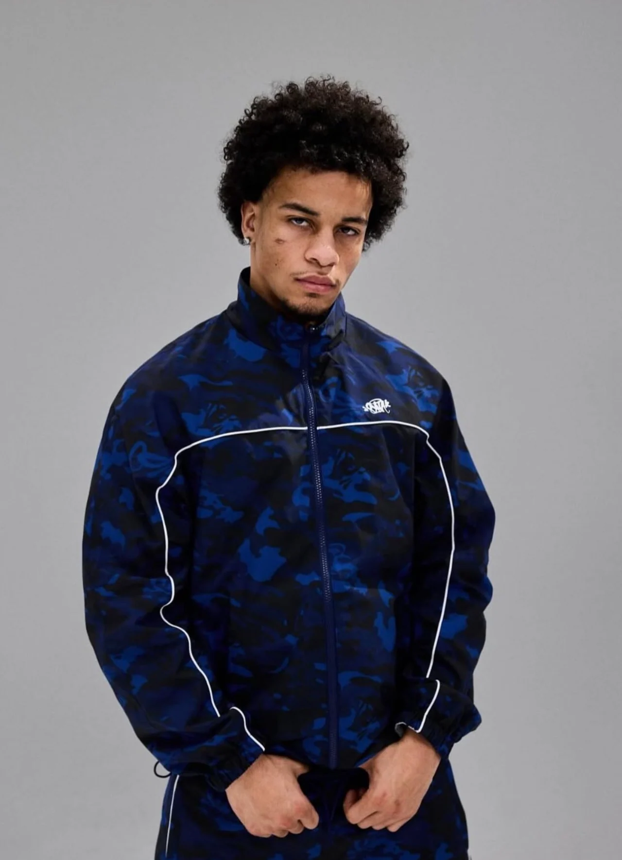 Josh wearing a blue patterned tracksuit in a studio