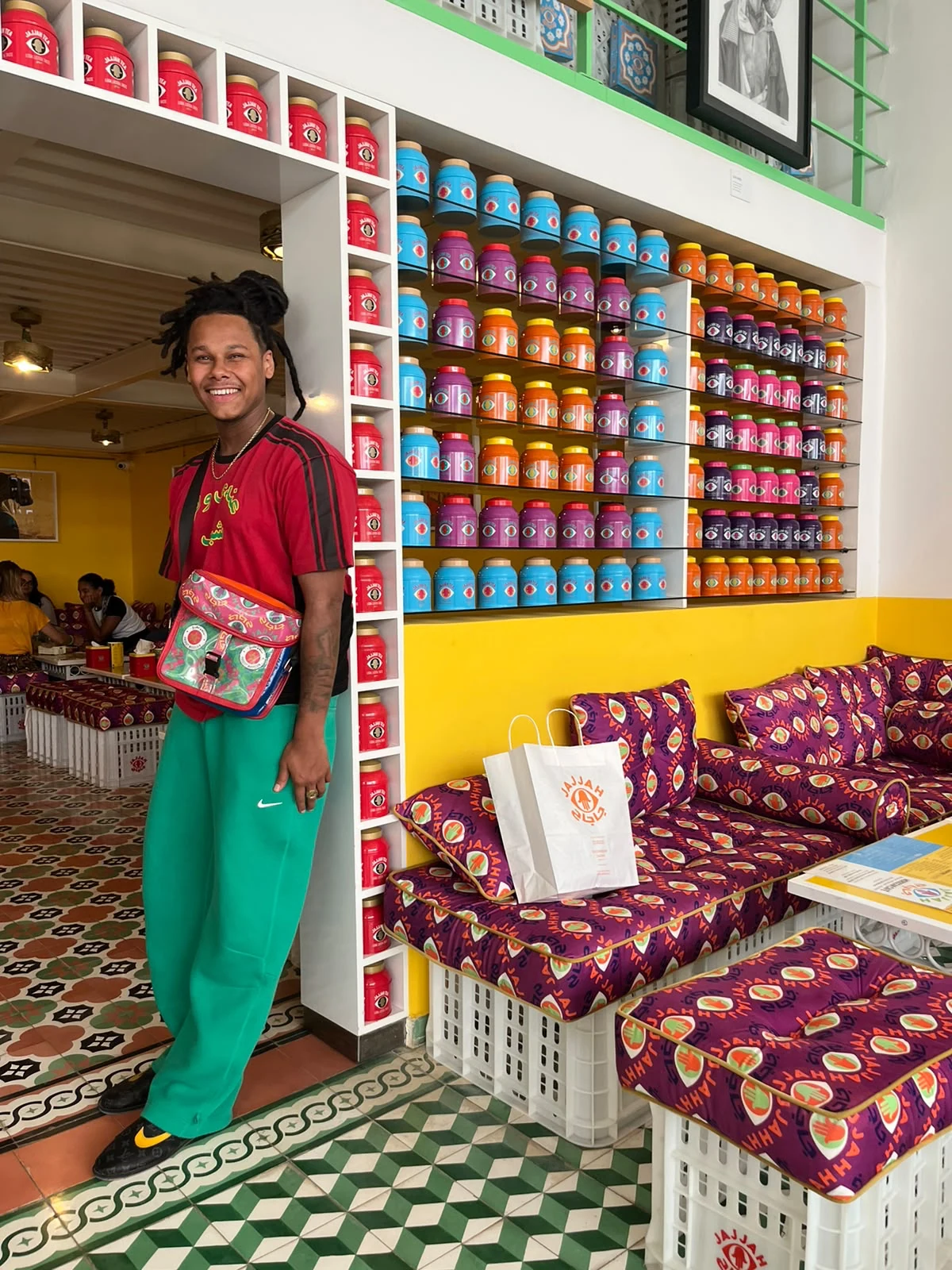 LZEE in a red shirt and green trousers in a colourful interior